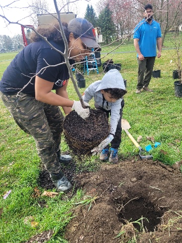 A person and a child planting a tree Description automatically generated