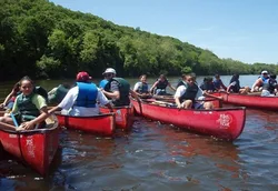 A group of people in canoes on a river

Description automatically generated