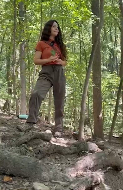 A woman dressed in casual clothing stands amidst a forest of tall, leafy trees.

AI-generated content may be incorrect.